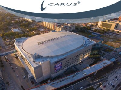 Aerial view of the Amway Center, a large arena with a round roof. Surrounding roads and buildings are visible. The arena has a white roof with the Amway Center logo. The scene is bathed in warm, golden light, indicating late afternoon or early evening.