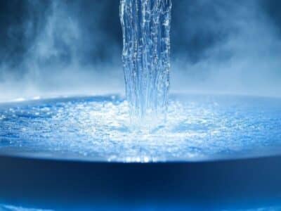 A circular fountain with water cascading into the center, surrounded by mist and illuminated with blue lighting, creating a serene and ethereal atmosphere.