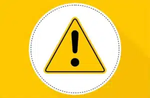 Yellow triangular warning sign with a black exclamation mark in the center, placed against a white circle with a dotted black border. The background is solid yellow, and the design casts a shadow to the right.