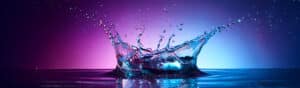 Water splash closeup with pink, purple, and blue hues in background for header image.